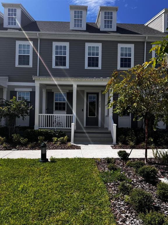 A gray multi-story townhouse features a covered front porch, white railings, and dormer windows — 2386 CELEBRATION BOULEVARD, CELEBRATION, FL