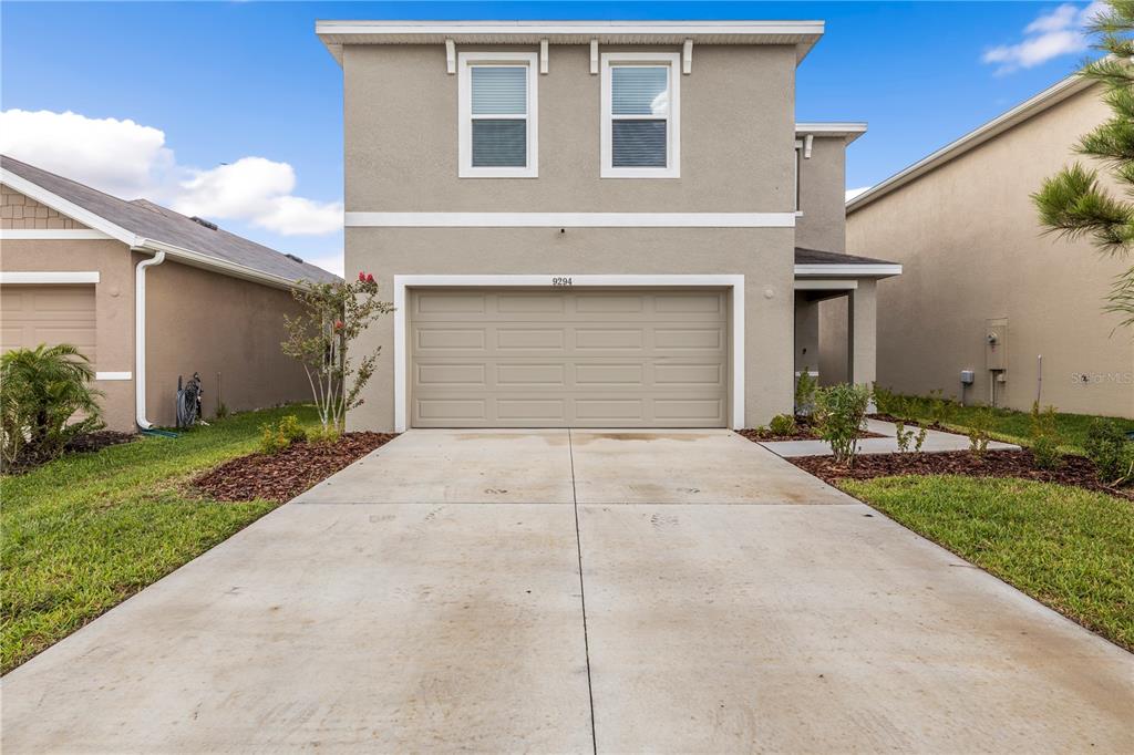 A two-story suburban house with a beige stucco exterior and a two-car garage — 9294 FORGE BREEZE LOOP, WESLEY CHAPEL, FL