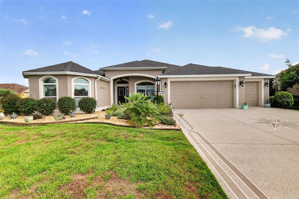 A single-story house with a beige exterior, a three-car garage, and a landscaped front yard — 1473 QUARTER TERRACE, THE VILLAGES, FL