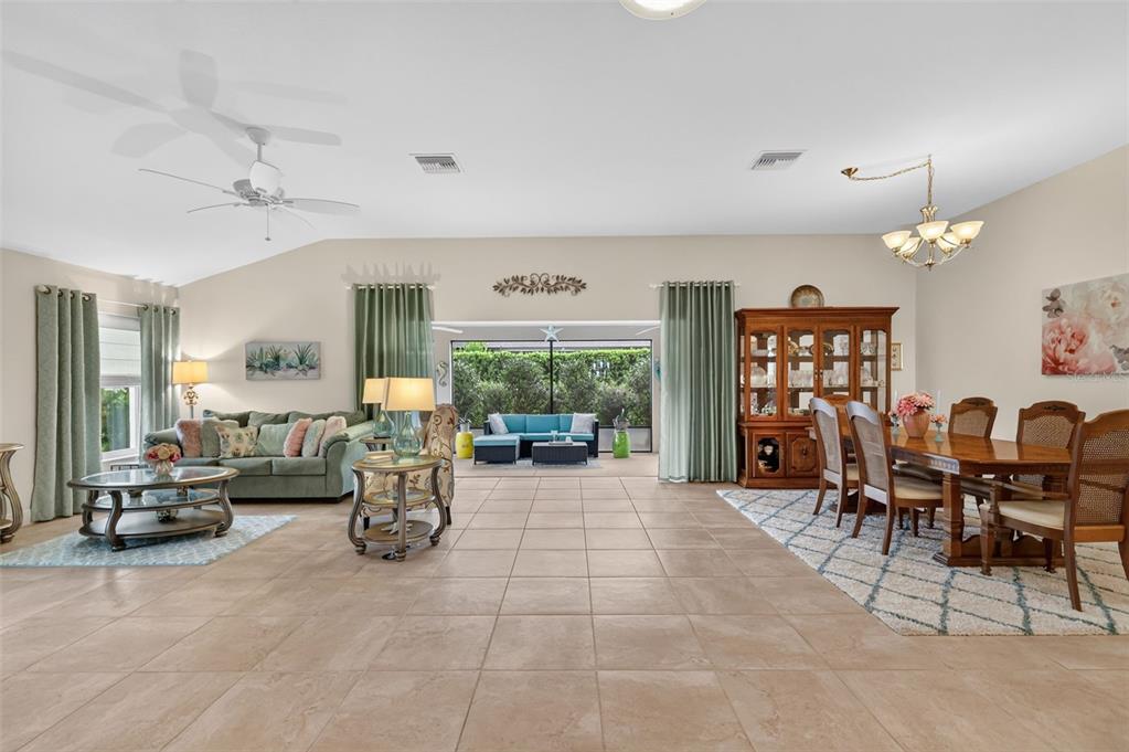A spacious open-concept living and dining area with tile floors, a ceiling fan, and patio access — 1473 QUARTER TERRACE, THE VILLAGES, FL