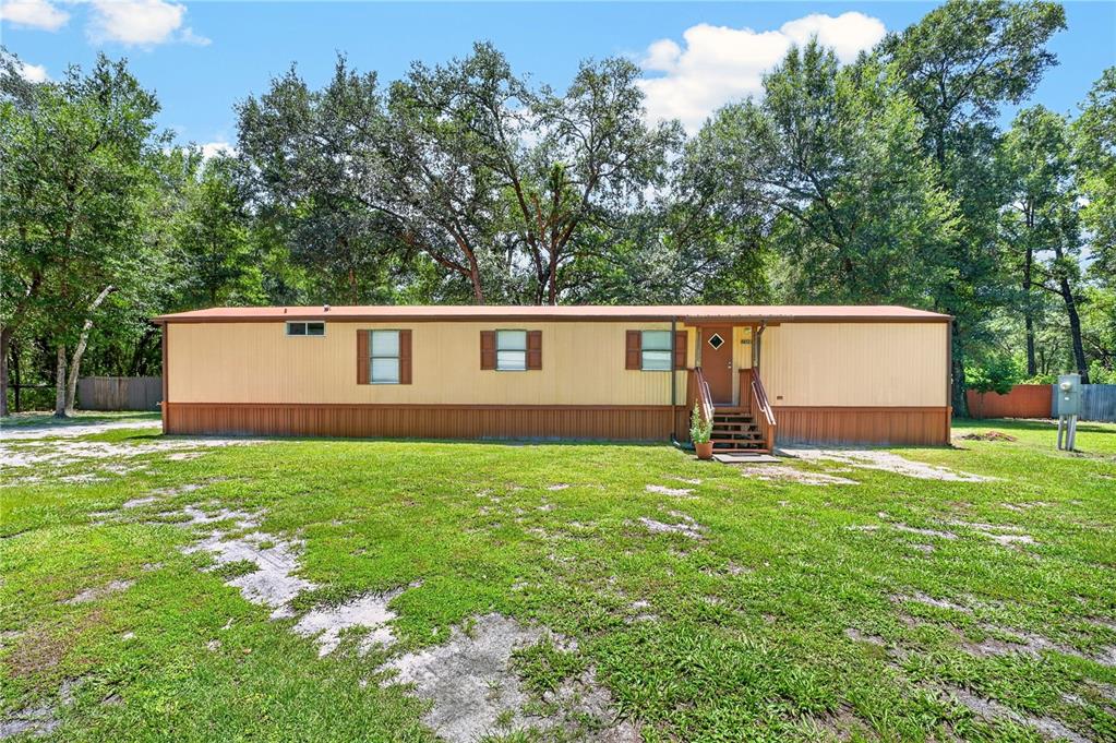 A single-story manufactured home with tan siding and brown trim sits on a grassy lot — 8200 SW 145 STREET, DUNNELLON, FL