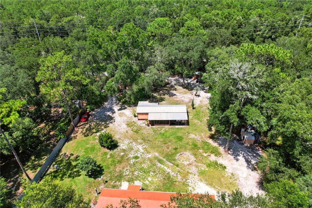 An aerial view shows a single-story house with a metal roof surrounded by wooded land — 8200 SW 145 STREET, DUNNELLON, FL