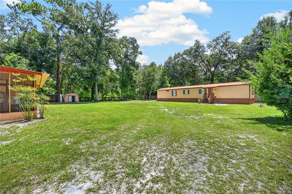 A large grassy yard features a mobile home, a small shed, and a screened porch — 8200 SW 145 STREET, DUNNELLON, FL
