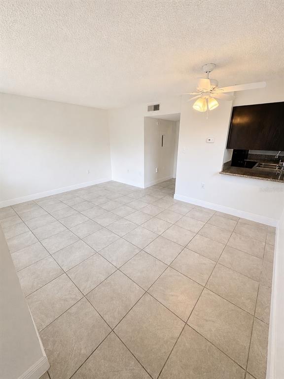 An empty room with light-colored tile flooring, a ceiling fan, and a kitchen pass-through window — 1183-1183 BENTLEY ROAD UNIT 4, LEESBURG, FL