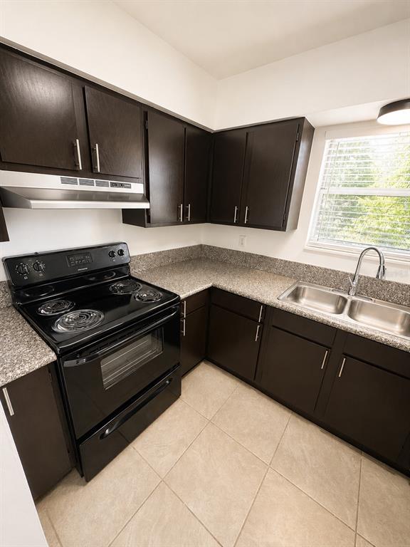 A kitchen with dark wood cabinets, granite countertops, a black stove, and a stainless sink — 1183-1183 BENTLEY ROAD UNIT 4, LEESBURG, FL