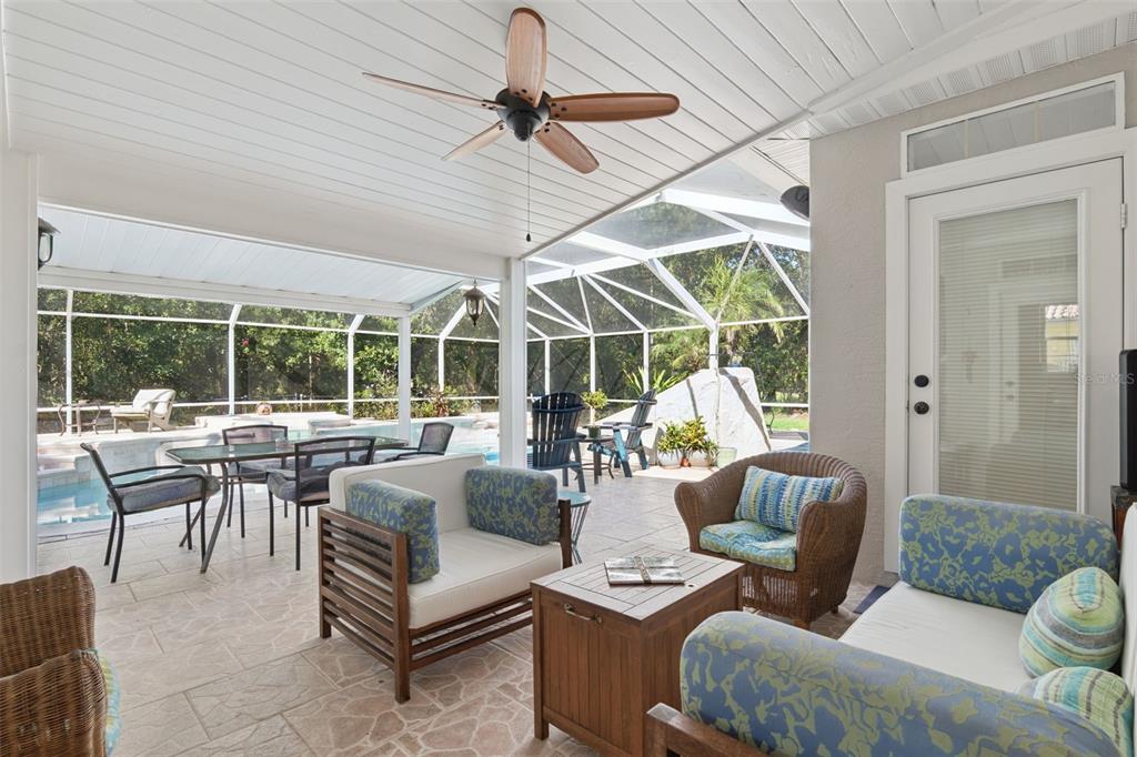 A covered patio features a ceiling fan, outdoor furniture, and a screened-in pool area — 11 FOXHUNTER FLAT, ORMOND BEACH, FL