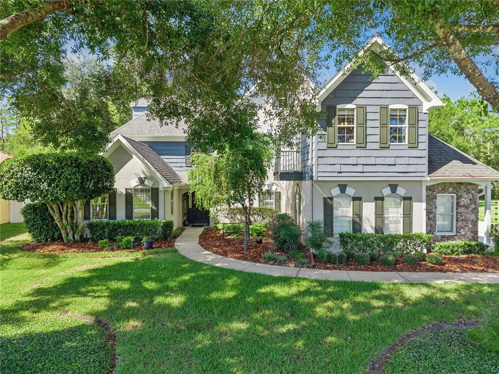 A two-story house with blue siding, stone accents, and a curved walkway through the front yard — 11 FOXHUNTER FLAT, ORMOND BEACH, FL