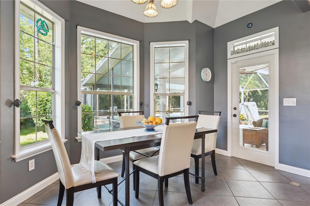 A dining area with gray walls, tile floors, a dark table, and large windows — 11 FOXHUNTER FLAT, ORMOND BEACH, FL