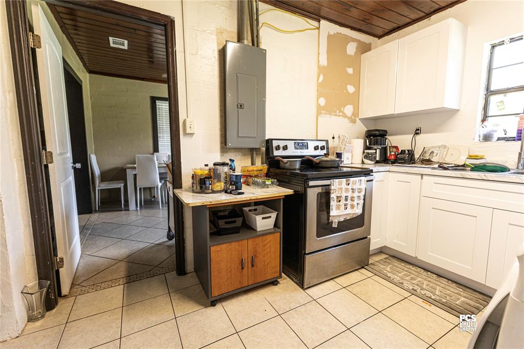 A kitchen features white cabinets, a stainless steel stove, and a mobile island — 7301 NW GAINESVILLE ROAD, OCALA, FL