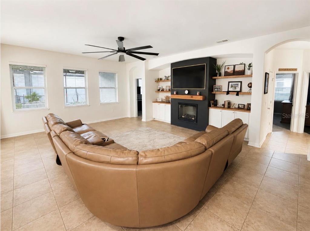 A living room features a large tan sectional sofa, tile flooring, and a black fireplace wall — 1518 RHODESWELL LANE, DOVER, FL
