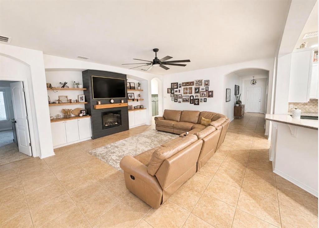 A living room features a fireplace with a dark accent wall, tan sectional, and tile flooring — 1518 RHODESWELL LANE, DOVER, FL