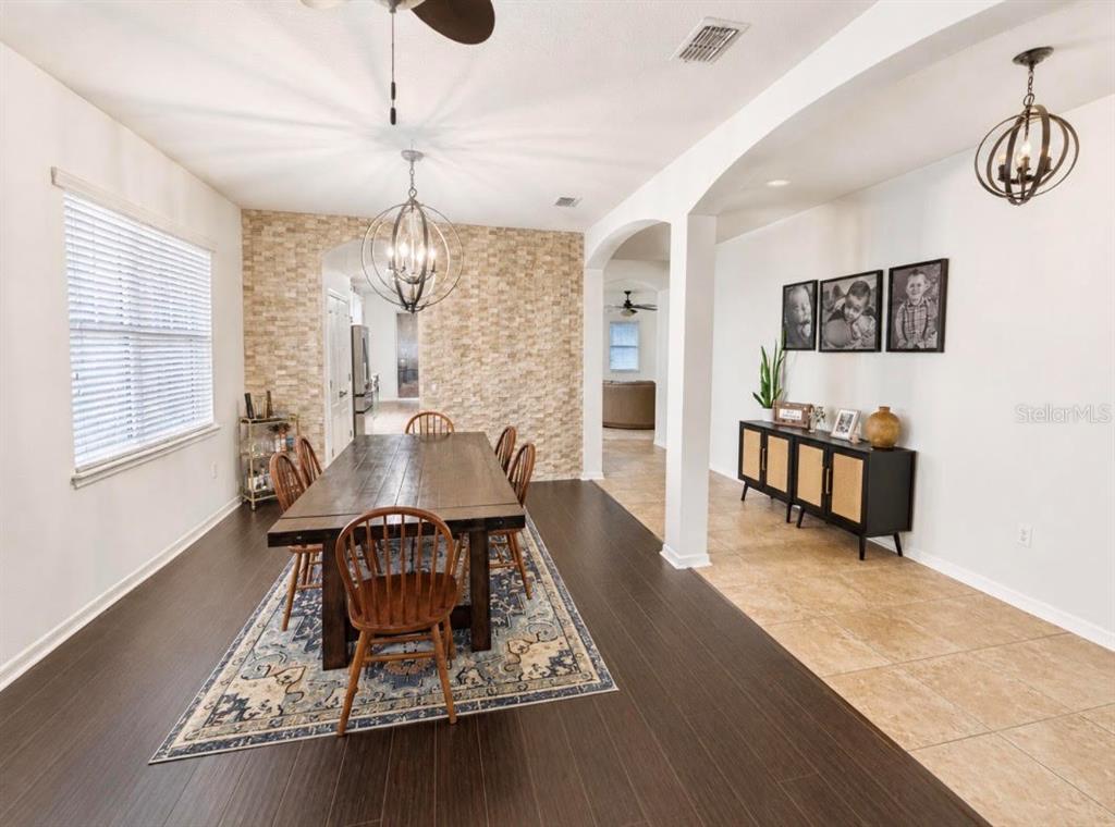 A dining room features a wooden table, stone accent wall, and dark hardwood flooring — 1518 RHODESWELL LANE, DOVER, FL
