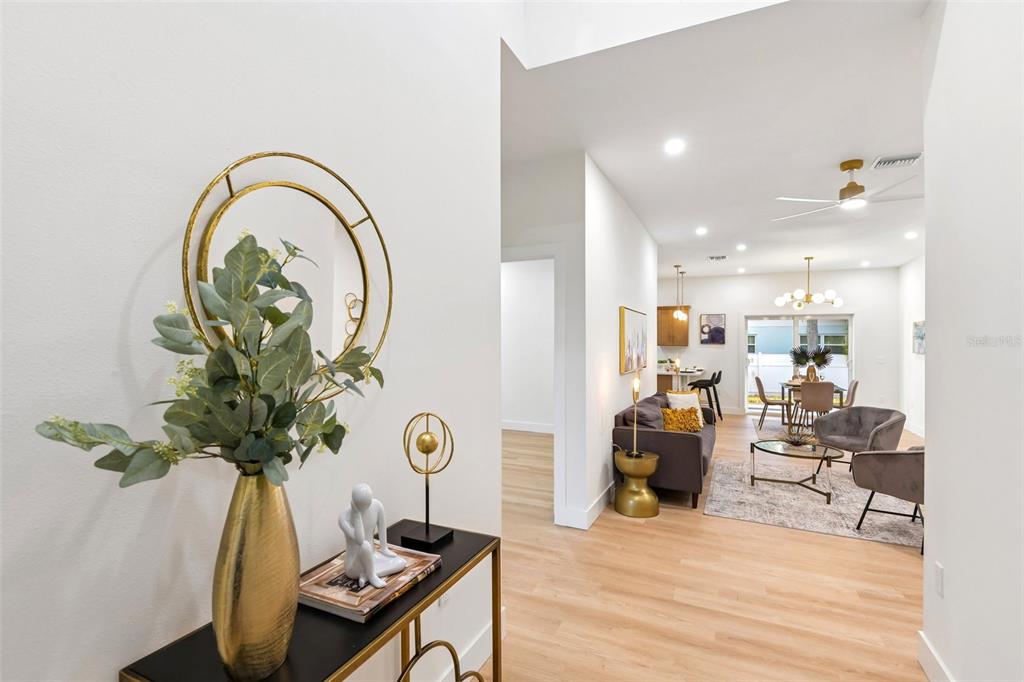 A view from a foyer into an open-concept living and dining area with light flooring — 266 PLATON AVENUE, DUNEDIN, FL