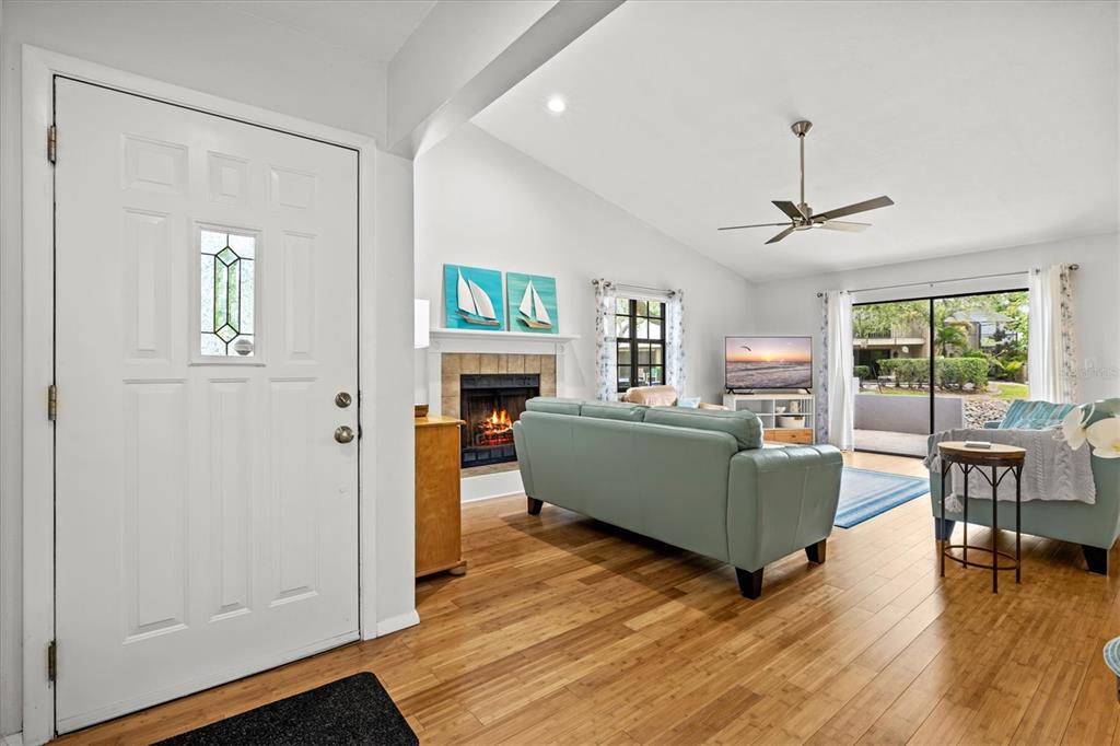 A living room features a fireplace, a light blue sofa, and a sliding glass door — 4566 HIDDEN VIEW PLACE UNIT 7, SARASOTA, FL