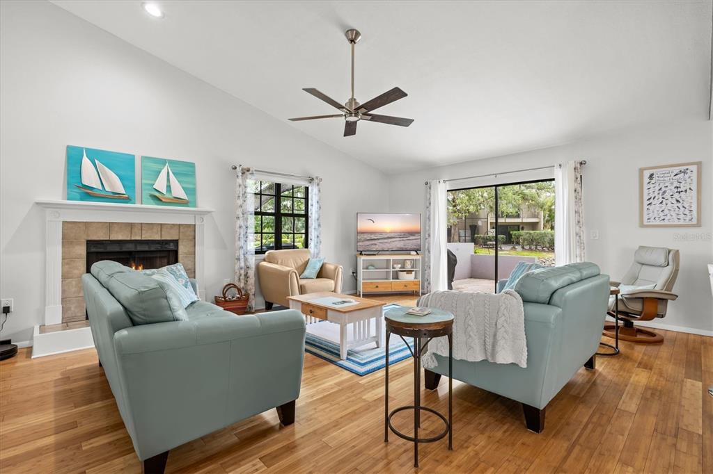 A living room features light blue sofas, a fireplace, and a sliding glass door — 4566 HIDDEN VIEW PLACE UNIT 7, SARASOTA, FL