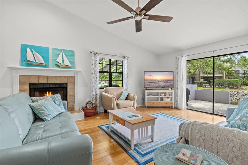A living room features a fireplace, light blue sofa, ceiling fan, and sliding glass doors — 4566 HIDDEN VIEW PLACE UNIT 7, SARASOTA, FL
