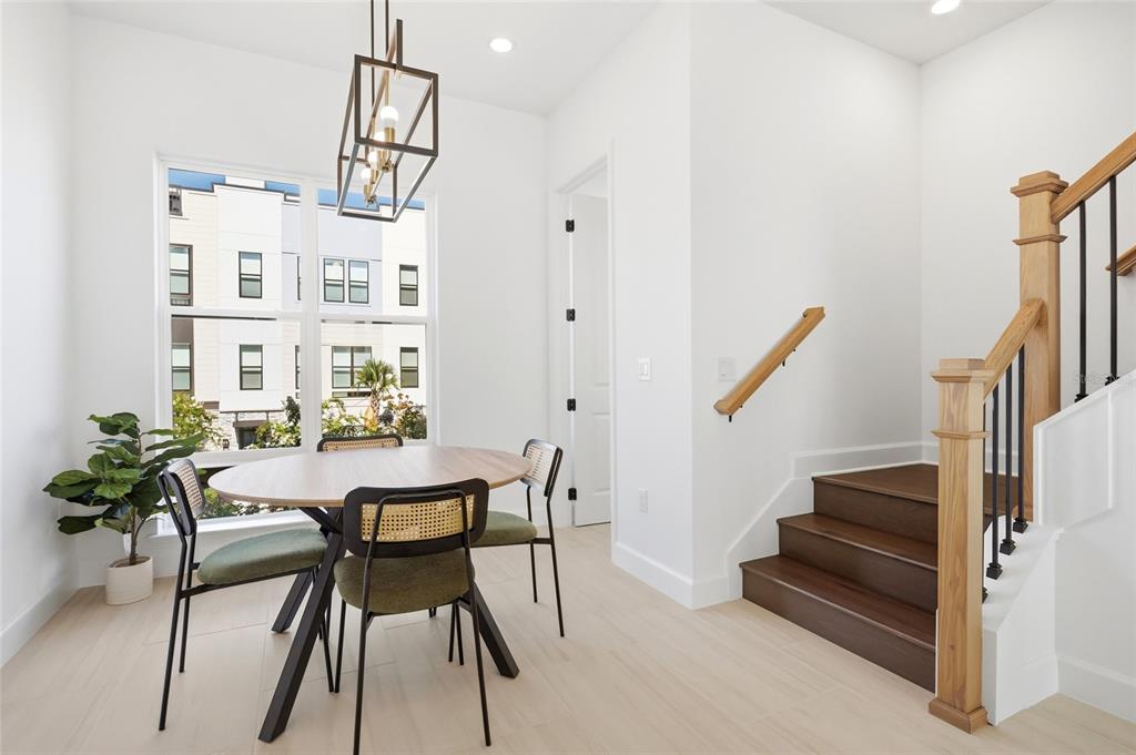 A dining area features a round table, modern chairs, a pendant light, and wooden stairs — 2130 WHITNEY MARSH ALLEY, ORLANDO, FL