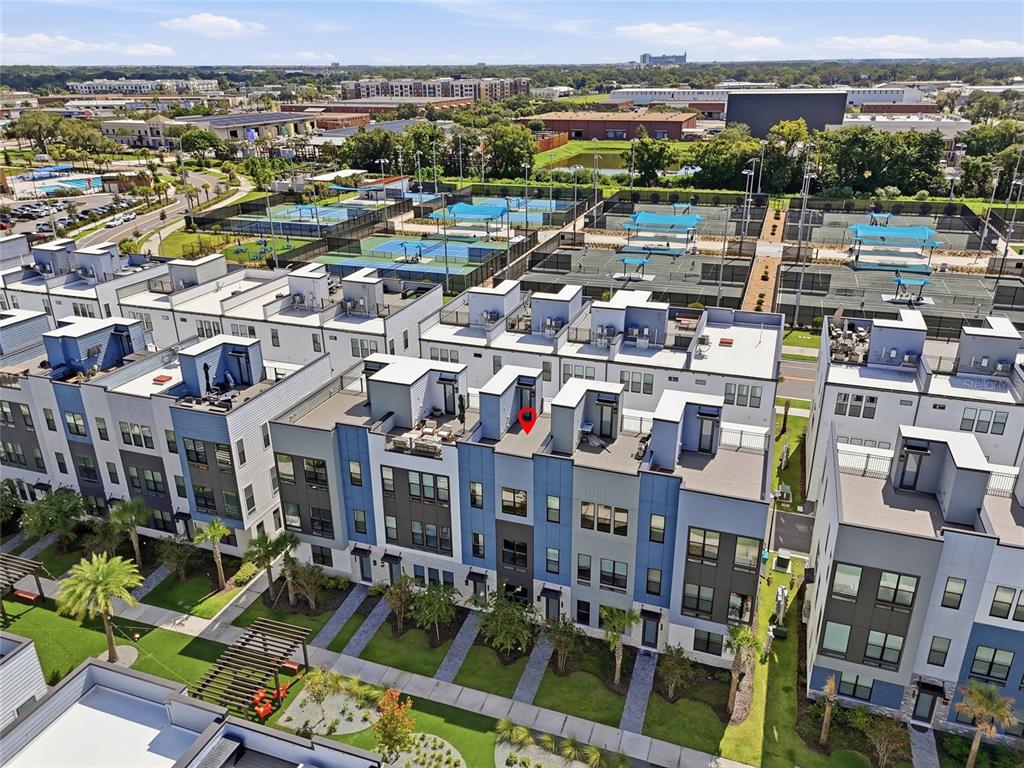 An aerial view shows a row of modern townhomes with rooftop terraces and nearby tennis courts — 2130 WHITNEY MARSH ALLEY, ORLANDO, FL