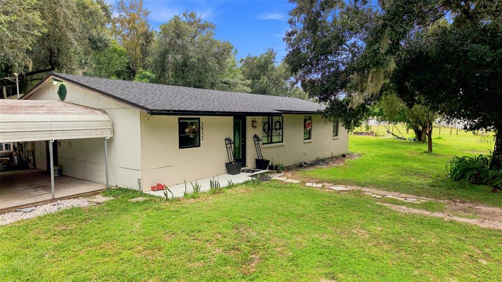 A single-story house with a carport, light-colored siding, and a dark shingled roof — 3812 REVEREND DAR DAR DRIVE, PLANT CITY, FL