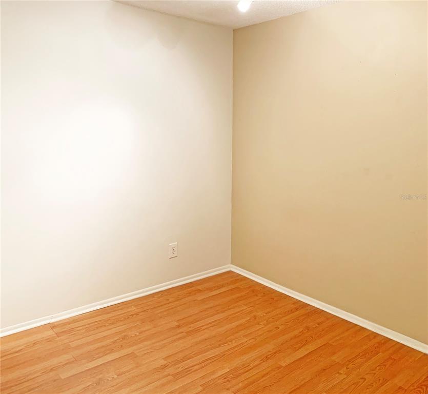 An empty room features light-colored walls, wood-look laminate flooring, and a white ceiling — 125 SPRINGWOOD CIRCLE UNIT D, LONGWOOD, FL