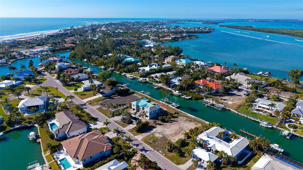 An aerial view shows waterfront homes along a canal leading toward the ocean — 721 EMERALD HARBOR DRIVE, LONGBOAT KEY, FL