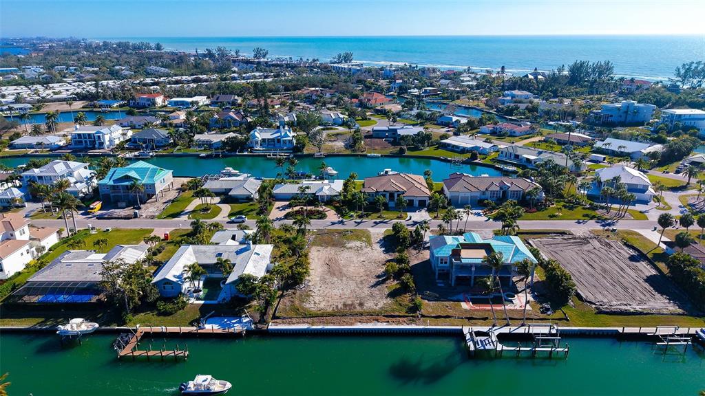 An aerial view of a waterfront residential neighborhood featuring a vacant lot between two houses — 721 EMERALD HARBOR DRIVE, LONGBOAT KEY, FL
