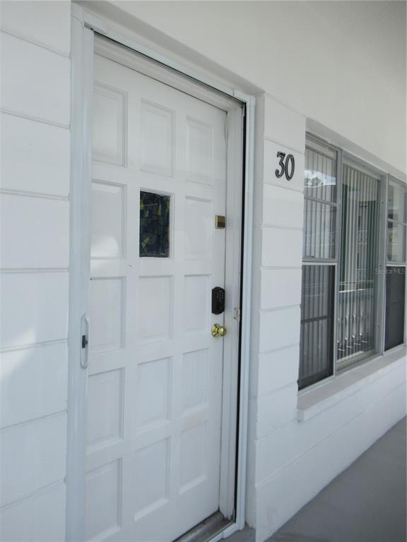 A white front door with a small decorative window and a digital keypad lock — 2468 FLORENTINE WAY UNIT 30, CLEARWATER, FL