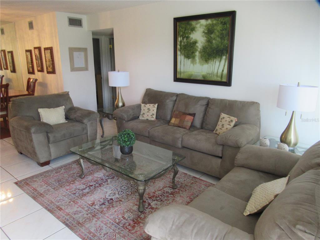 A living room features a brown sofa, loveseat, armchair, glass coffee table, and a patterned rug — 2468 FLORENTINE WAY UNIT 30, CLEARWATER, FL