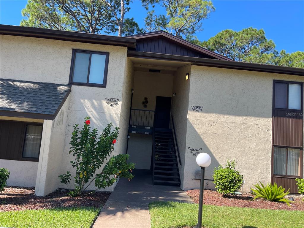 An exterior view of a two-story apartment building with stairs leading to upper units — 647 MIDWAY DRIVE UNIT B, OCALA, FL