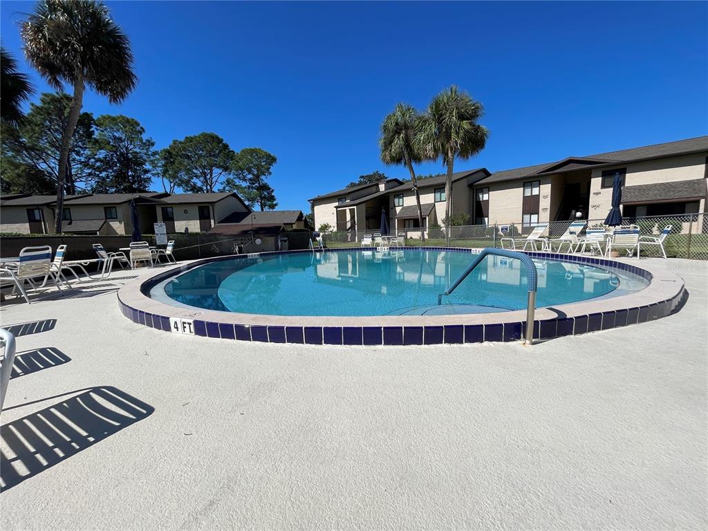 A circular swimming pool is surrounded by a concrete deck, lounge chairs, and apartment buildings — 647 MIDWAY DRIVE UNIT B, OCALA, FL