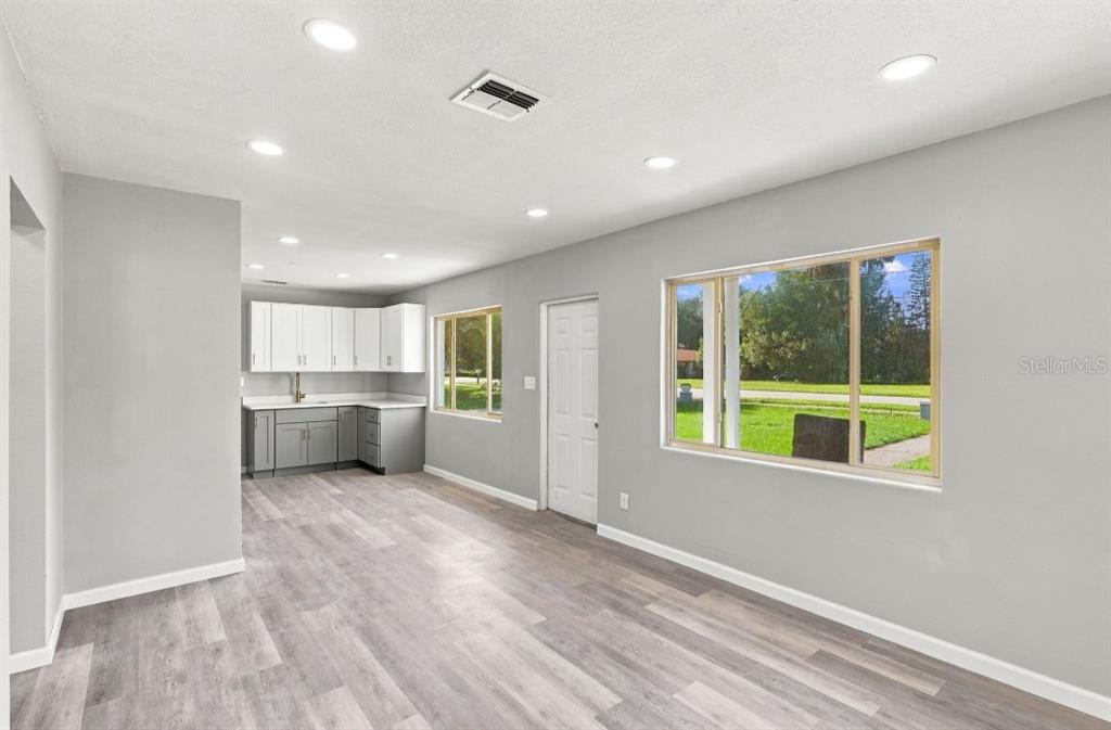 A kitchen with white upper cabinets and gray lower cabinets opens into a living area — 8 SMYRNA DRIVE, DEBARY, FL