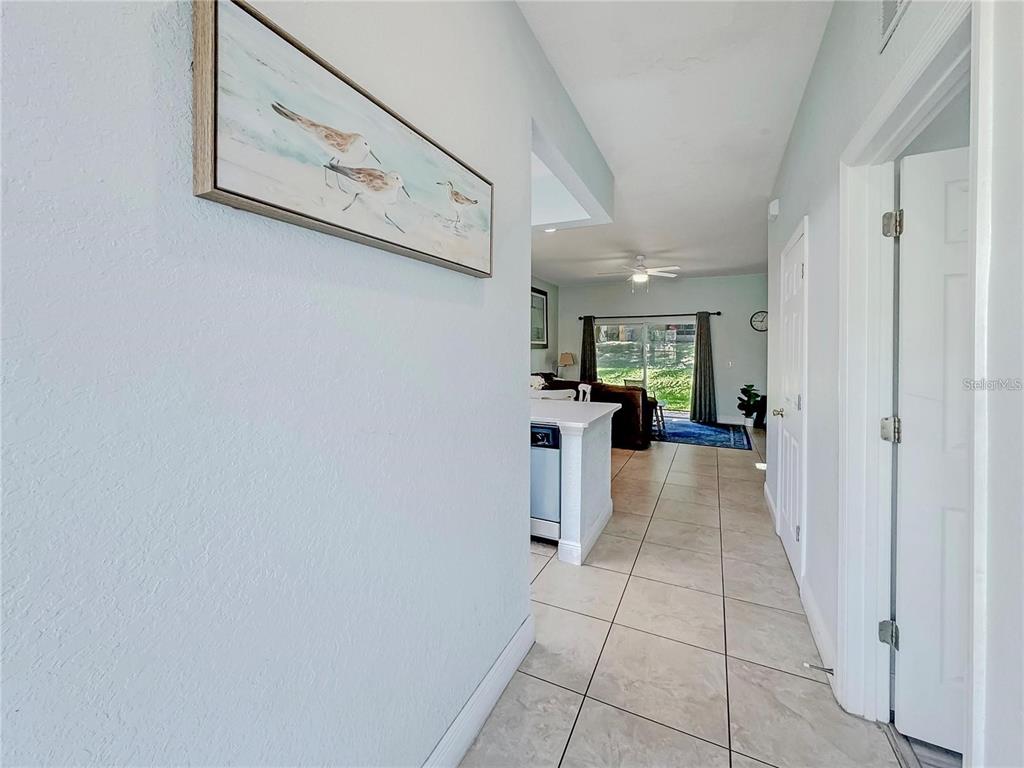 A hallway with light-colored walls and tile flooring leads into an open-concept living area — 130 PALERMO STREET, DAVENPORT, FL