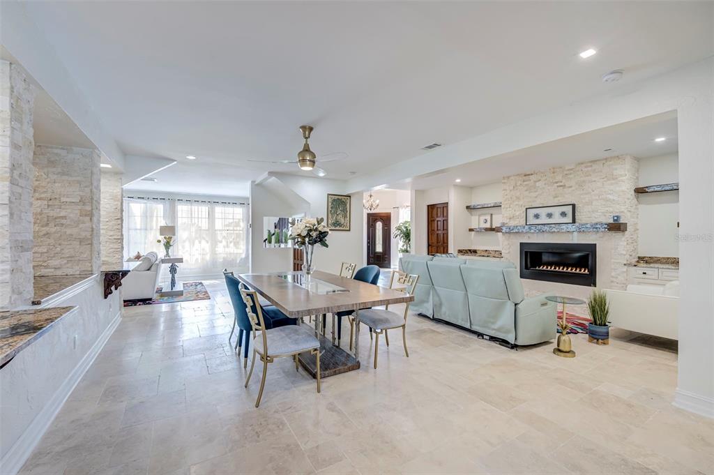 An open-concept living and dining area features tile flooring, a stone fireplace, and modern furniture — 2491 PALM TREE DRIVE, PUNTA GORDA, FL