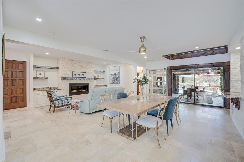 A dining and living area features a stone fireplace, tile flooring, and sliding glass doors — 2491 PALM TREE DRIVE, PUNTA GORDA, FL