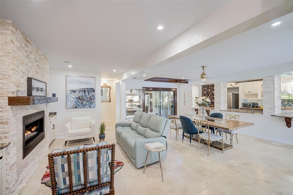 An open-concept living and dining area features a stone fireplace, light-colored tile flooring, and furniture — 2491 PALM TREE DRIVE, PUNTA GORDA, FL