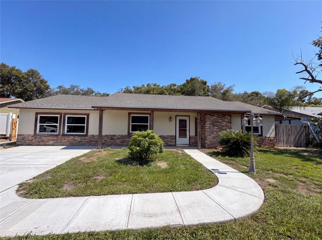 A single-story house with a stone facade, a covered porch, and a concrete walkway — 466 LELAND DRIVE, DELTONA, FL