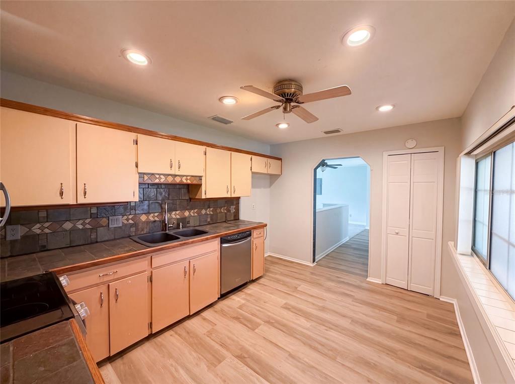 A kitchen with light-colored cabinets, dark tile countertops, a ceiling fan, and wood-look flooring — 466 LELAND DRIVE, DELTONA, FL