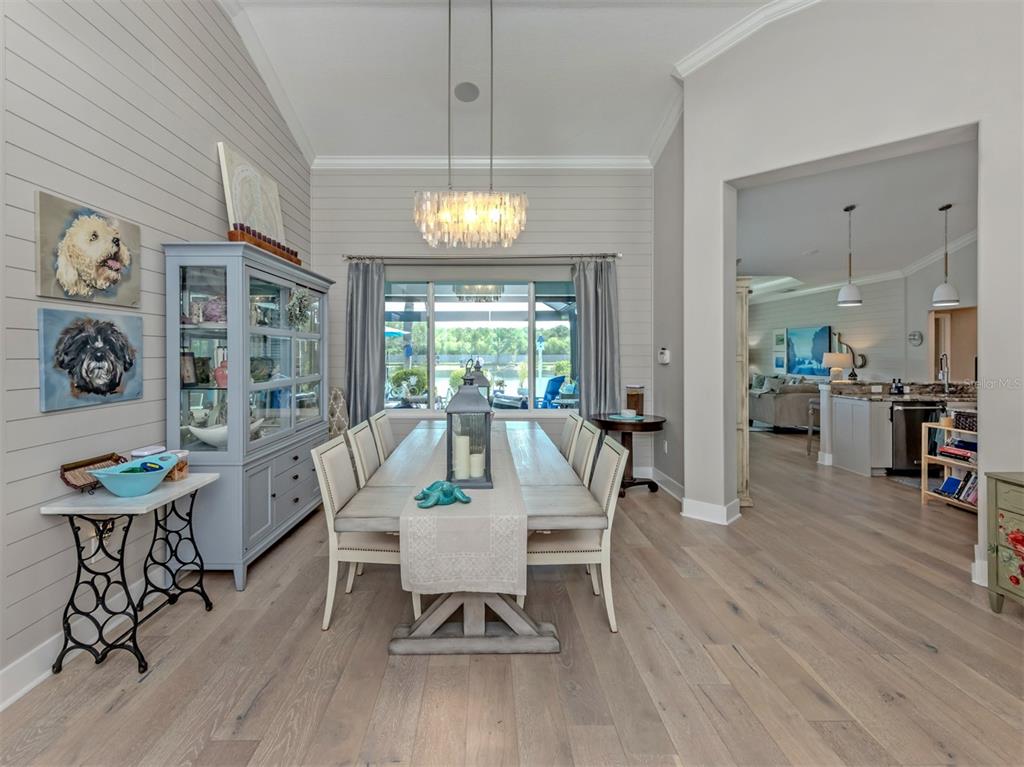 A dining room features a long wooden table, a blue hutch, and light wood flooring — 132 WADING BIRD DRIVE, VENICE, FL