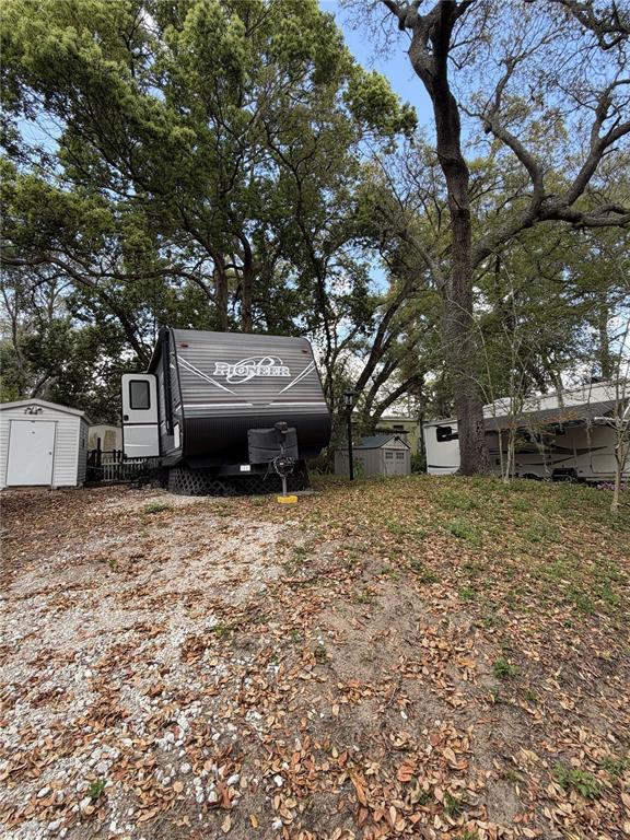 A Pioneer travel trailer is parked on a gravel lot near trees and storage sheds — 3000 CLARCONA ROAD UNIT 743, APOPKA, FL