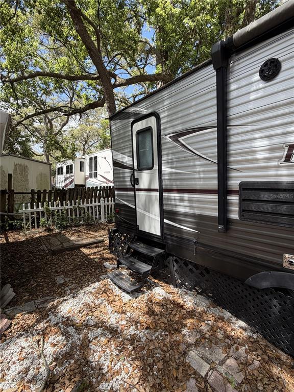 A travel trailer is parked on a gravel lot next to a white picket fence — 3000 CLARCONA ROAD UNIT 743, APOPKA, FL