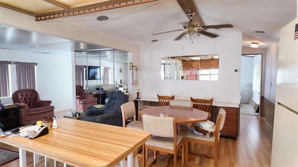 A dining area with a wooden table and chairs sits adjacent to a living room — 9000 US HIGHWAY 192 UNIT 372, CLERMONT, FL
