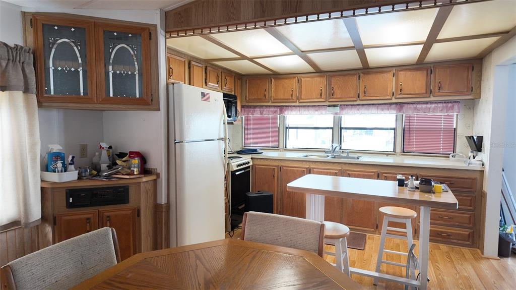 A kitchen with wood cabinets, a white refrigerator, a breakfast bar, and a drop ceiling — 9000 US HIGHWAY 192 UNIT 372, CLERMONT, FL