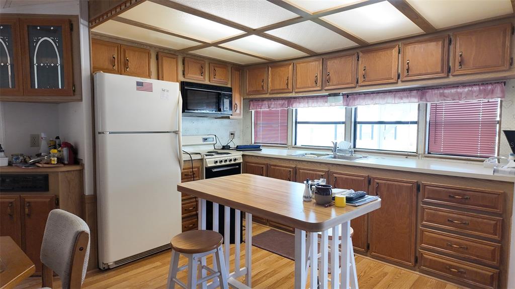 A kitchen features wood cabinets, a white refrigerator, a central island, and a drop ceiling — 9000 US HIGHWAY 192 UNIT 372, CLERMONT, FL