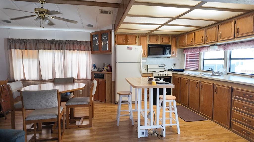 A kitchen and dining area with wood cabinets, a white refrigerator, and a central island — 9000 US HIGHWAY 192 UNIT 372, CLERMONT, FL
