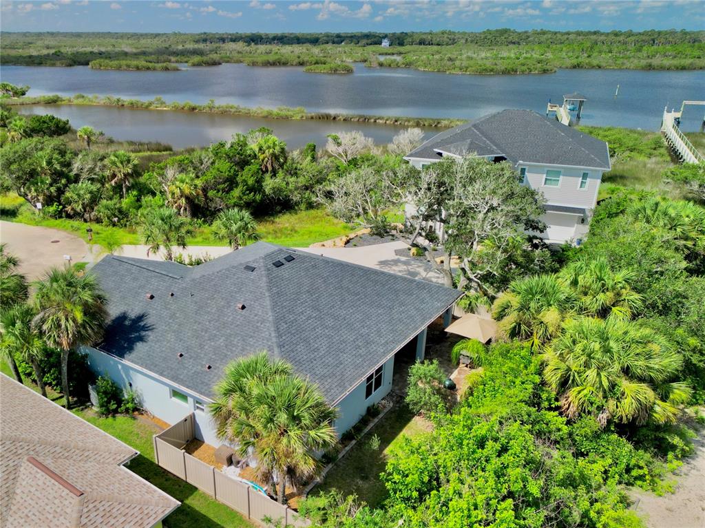 An aerial view shows two houses near a body of water surrounded by lush vegetation — 63 BEACHWOOD DRIVE, FLAGLER BEACH, FL