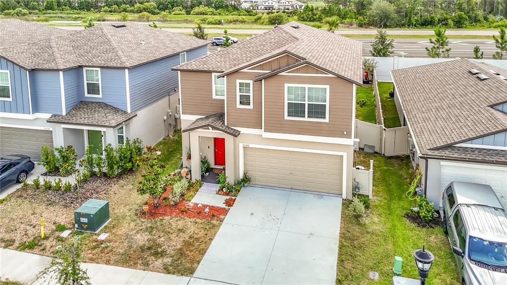 An aerial view shows a two-story suburban house with a tan exterior and red door — 35186 ACKLEY TRACE, ZEPHYRHILLS, FL