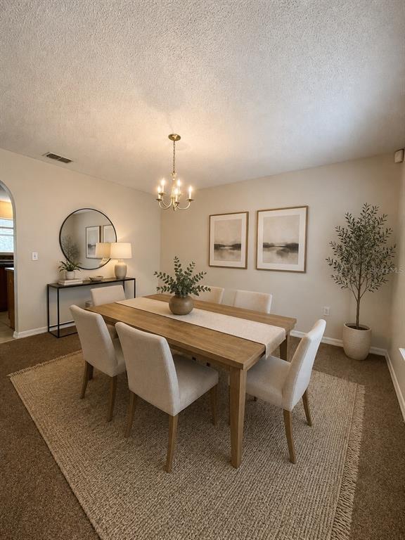 A dining room features a wooden table with six chairs, a chandelier, and wall art — 1304 DOVER DRIVE, KISSIMMEE, FL