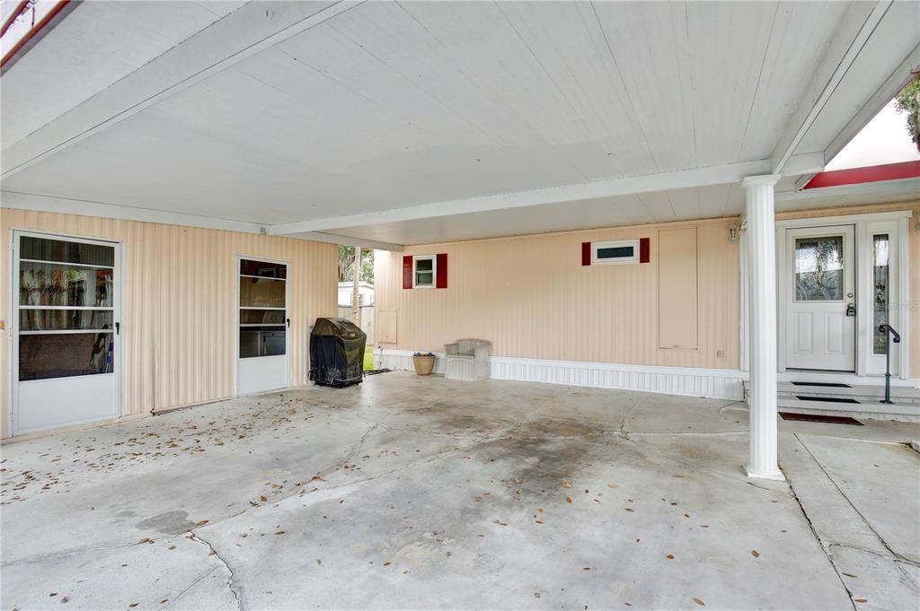 A covered concrete carport area features a light-colored exterior wall with two doors and windows — 105 CANAL VIEW, EUSTIS, FL