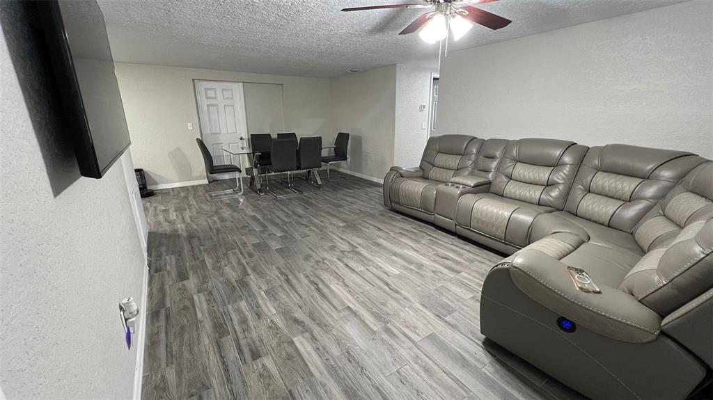 A living room with gray wood-look flooring, a large sectional sofa, and a dining area — 2705 GARDNER PLACE, HOLIDAY, FL