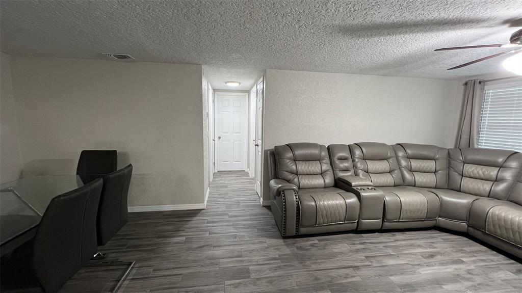 A living room and dining area feature gray wood-look flooring and a large sectional sofa — 2705 GARDNER PLACE, HOLIDAY, FL
